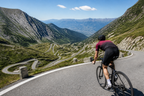 Road cyclist descending a smooth mountain pass in clear weather