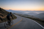 Cyclist planning a route on a ridge road with mountains ahead